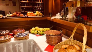 Mesa de buffet com frutas, doces e cestas de pão.