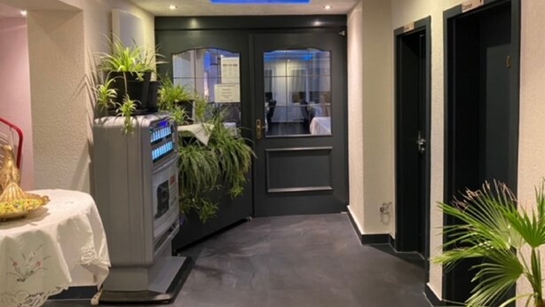 Um corredor com design de teto moderno, uma receç ão com plantas e uma porta que dá para um quarto.