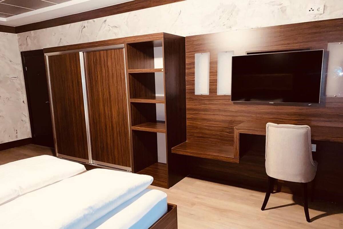 A bedroom with a bed, a wardrobe, a desk, and a TV.