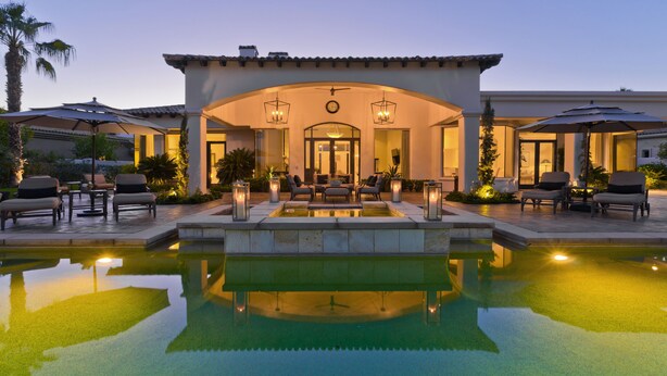 A luxurious outdoor pool area with a patio, seating, and ambient lighting. - Stunning PGA  Home with Privacy and Lake Views on Golf Course (La Quinta)
