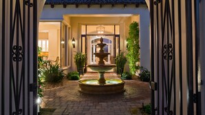 A courtyard with a central fountain, surrounded by a brick pathway and potted plants. - Stunning PGA  Home with Privacy and Lake Views on Golf Course (La Quinta)