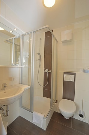 A modern bathroom with a glass-enclosed shower, a sink, and a toilet. - Hotel Gasthof Rotes Rovu (Heroldsberg)