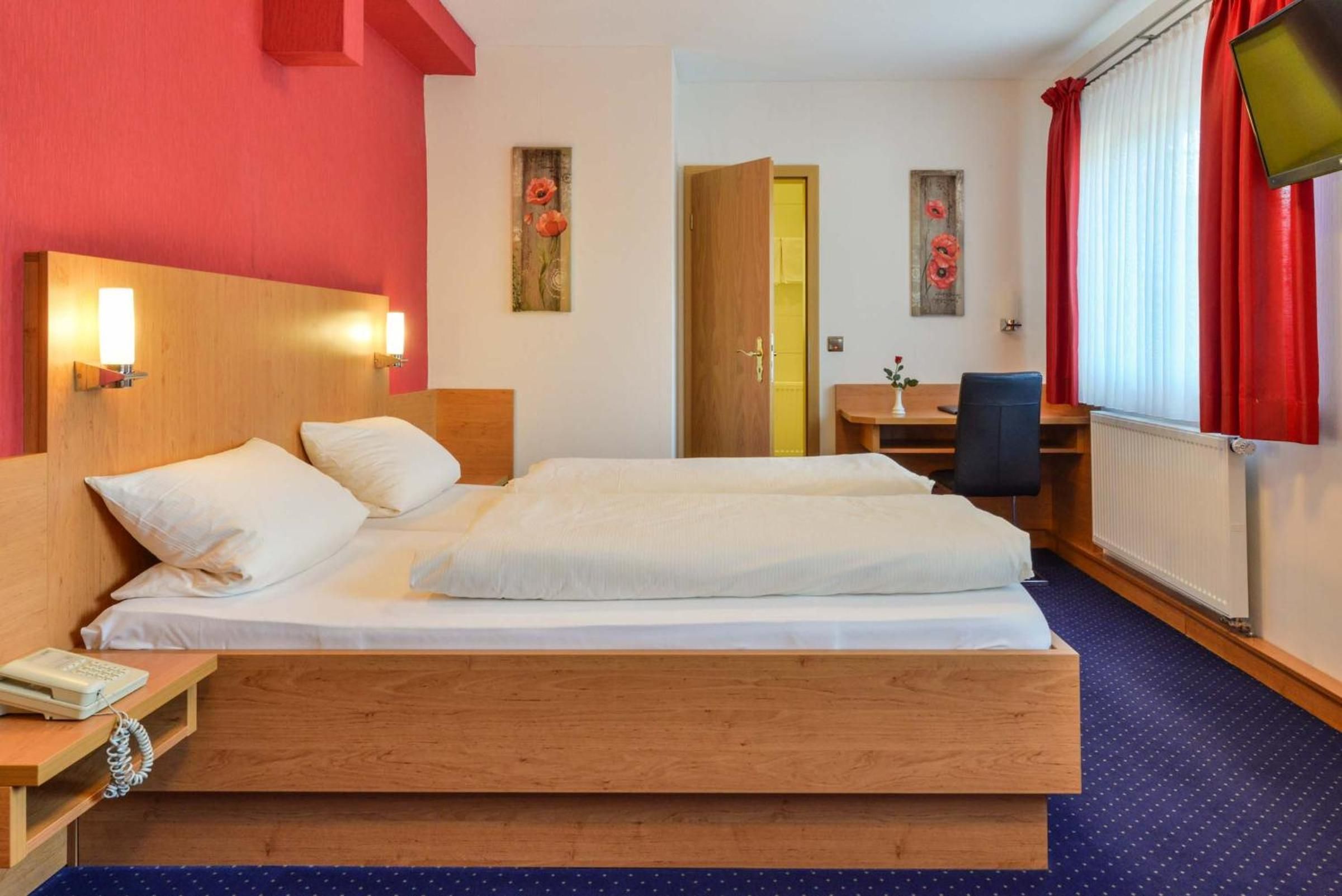 A hotel room with a large bed, bedside tables, a desk, and a chair.