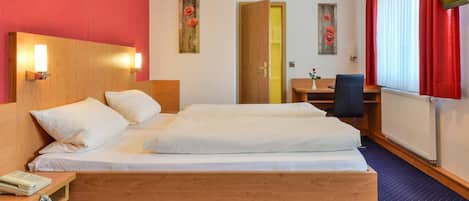 A hotel room with a large bed, bedside tables, a desk, and a chair.