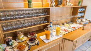 A buffet setup with various food items, a selection of wine glasses, and a coffee station.