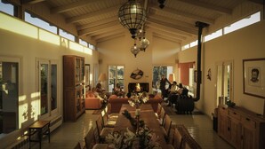 A spacious living room with a fireplace, large windows, and a high ceiling. - The Lodge Ronda (Ronda)