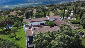 A large, two-story house with a tiled roof, surrounded by lush greenery and trees. - The Lodge Ronda (Ronda)
