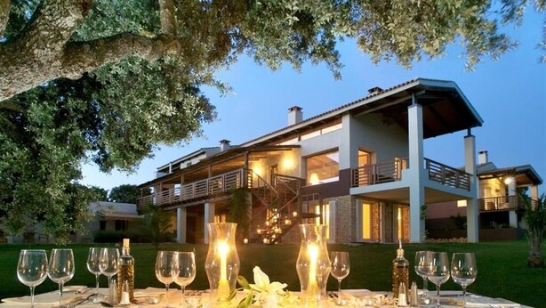 A modern two-story house with a dining area set up for an outdoor meal, featuring a table with wine glasses and a candle. - The Lodge Ronda (Ronda)