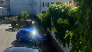 A residential area with a white house, a blue car parked in the driveway, and a clear blue sky. - Gasthaus zum Adler (Ettenheim)
