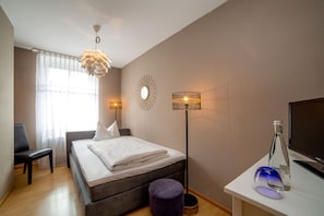 A bedroom with a bed, bedside lamps, a desk with a computer, and a window with curtains. - Gasthaus zum Adler (Ettenheim)