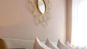 A hotel room with a bed, pillows, a lamp, and a decorative mirror on the wall. - Gasthaus zum Adler (Ettenheim)