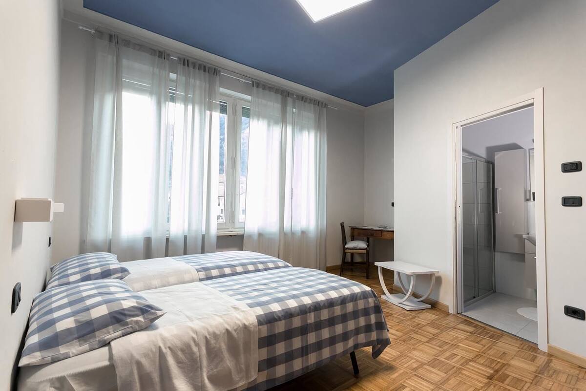 A bedroom with a bed, a desk, and a bathroom.