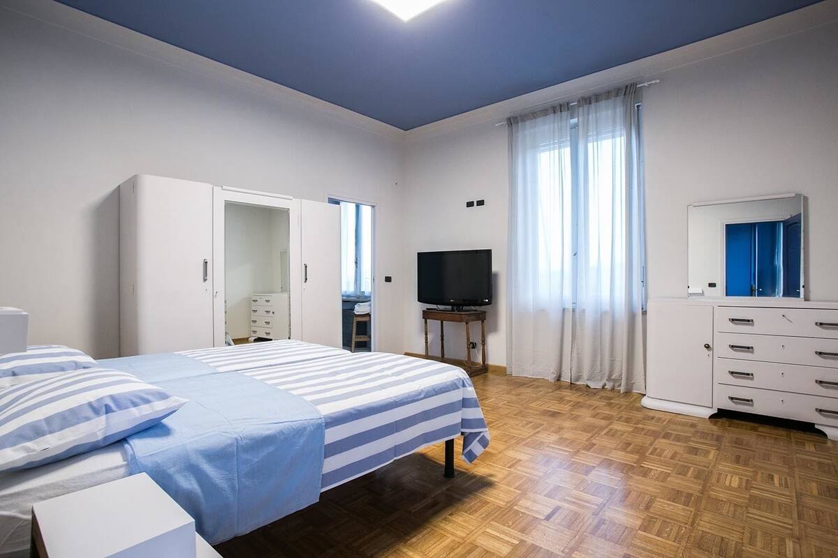 A bedroom with a bed, a TV, a wardrobe, and a dresser.