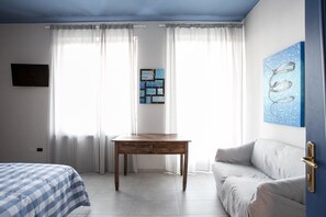A hotel room with a bed, a wooden table, a sofa, and a painting on the wall. - Boulevard 900 - Comfort and Style - Entire Structure 12 Beds (Revello)