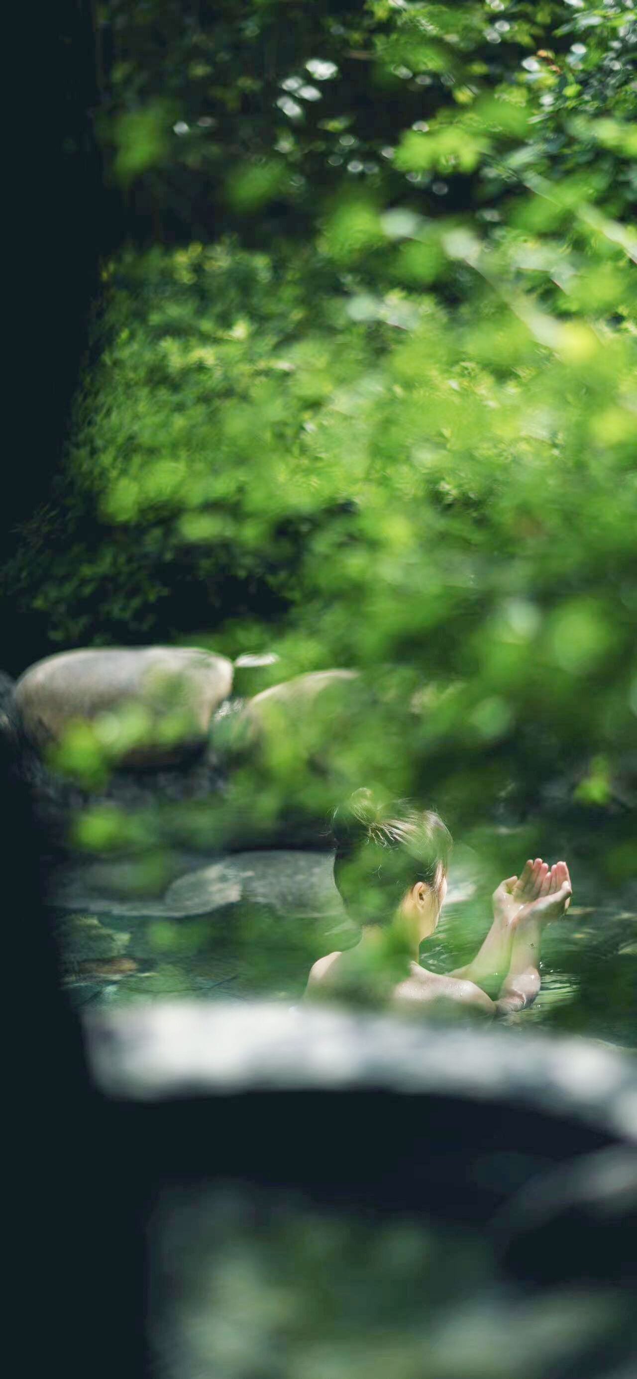 A person in a natural setting with greenery and rocks.