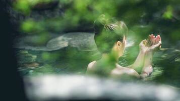 A person in a natural setting with greenery and rocks.