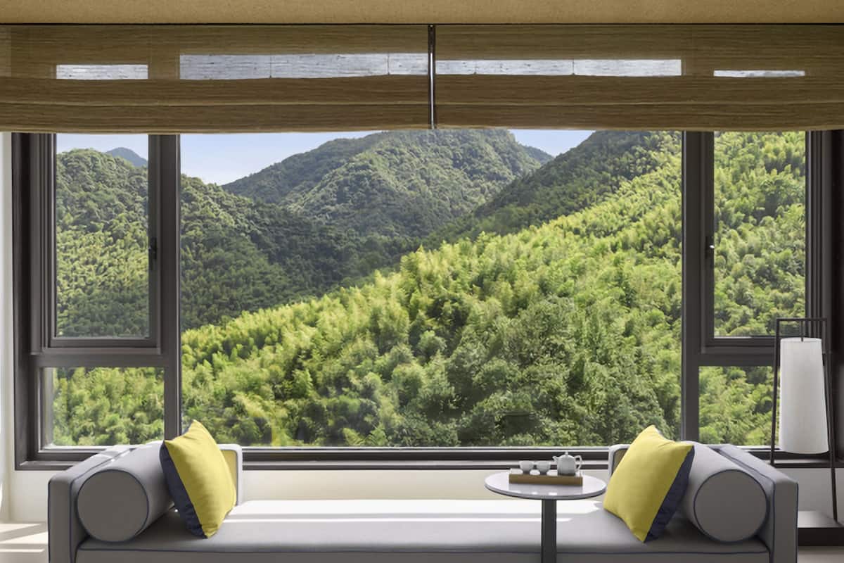 Ein Zimmer mit großem Fenster und Blick auf eine bewaldete Bergkette.