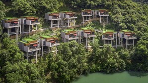 Un moderno resort ecológico con varias construcciones flotantes, rodeado de exuberante vegetación y un río.