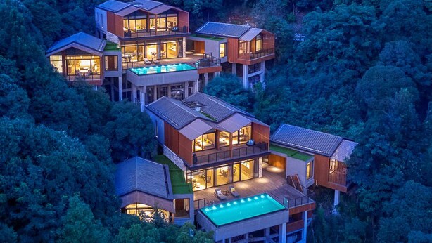 Una casa moderna de varios pisos con grandes ventanales, varios balcones y una piscina.