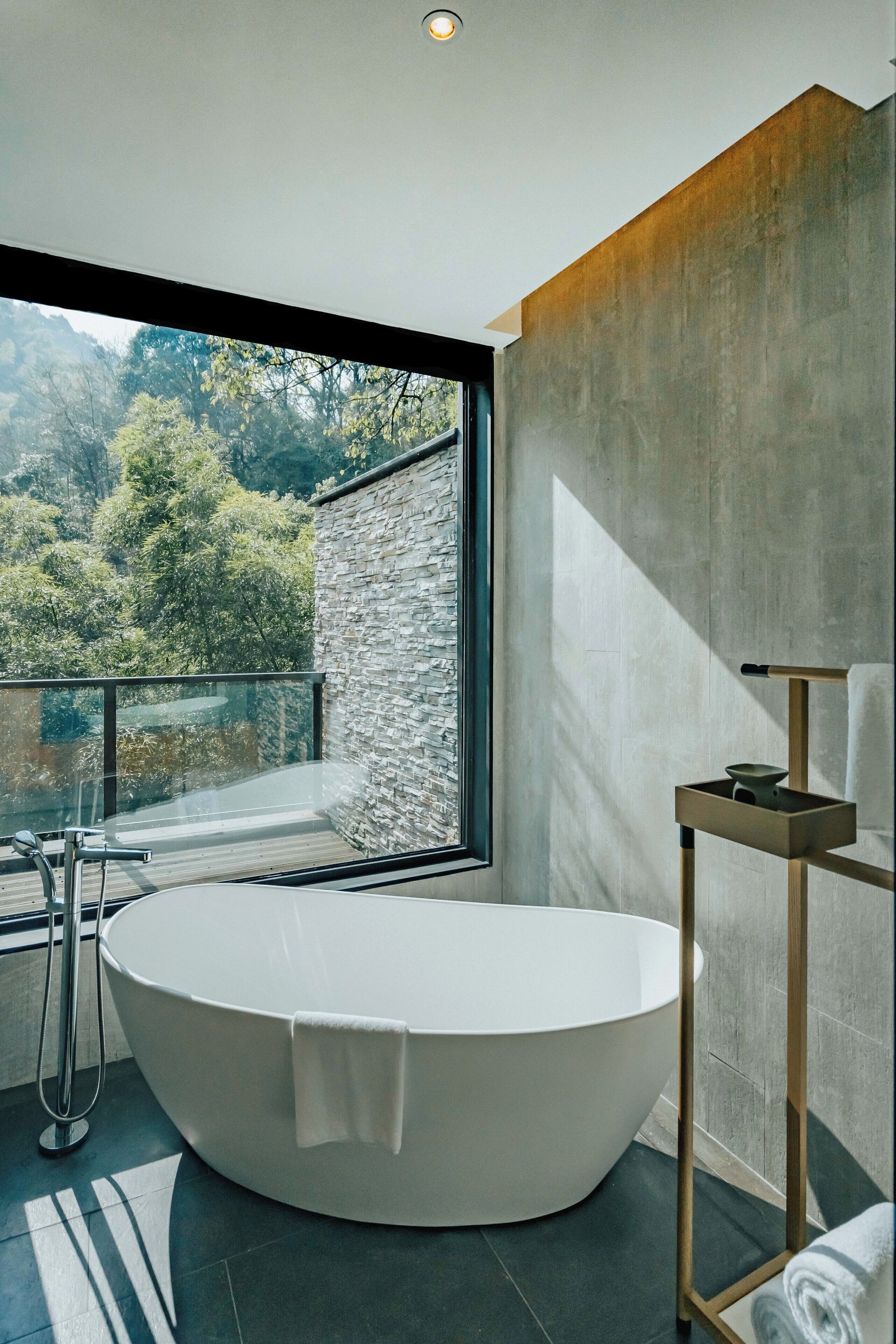 Ein modernes Badezimmer mit einer freistehenden Badewanne, einer Glasdusche und Blick auf eine Berglandschaft.