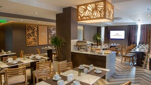 Comedor de hotel con varias mesas, sillas y una barra de cocina.