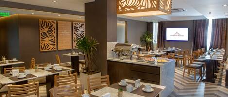 Comedor de hotel con varias mesas, sillas y una barra de cocina.