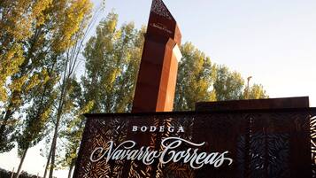 Un monumento alto y esbelto con una parte superior puntiaguda y una base con un panel de metal decorativo que muestra el texto "BODEGA Navarro Correas".
