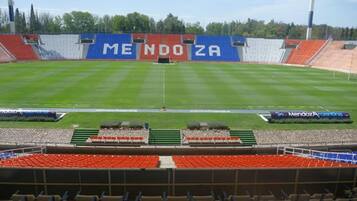 A stadium with a large blue banner reading "MENDOZA" and a green field.