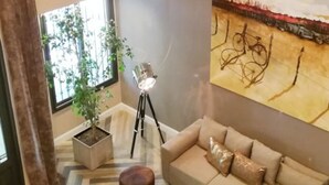 Una sala de estar moderna con un sofá, una lámpara de pie y un cuadro abstracto grande en la pared.