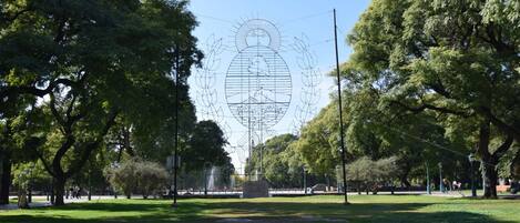 A park with a large sculpture in the center, surrounded by trees and a fountain.