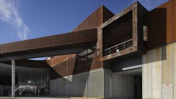 Um edifício moderno com telhado plano, amplos espaços abertos e uma escadaria que leva a um andar superior.