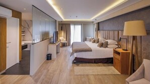 Una habitación de hotel moderna con una cama grande, mesitas de noche, televisión y un armario.