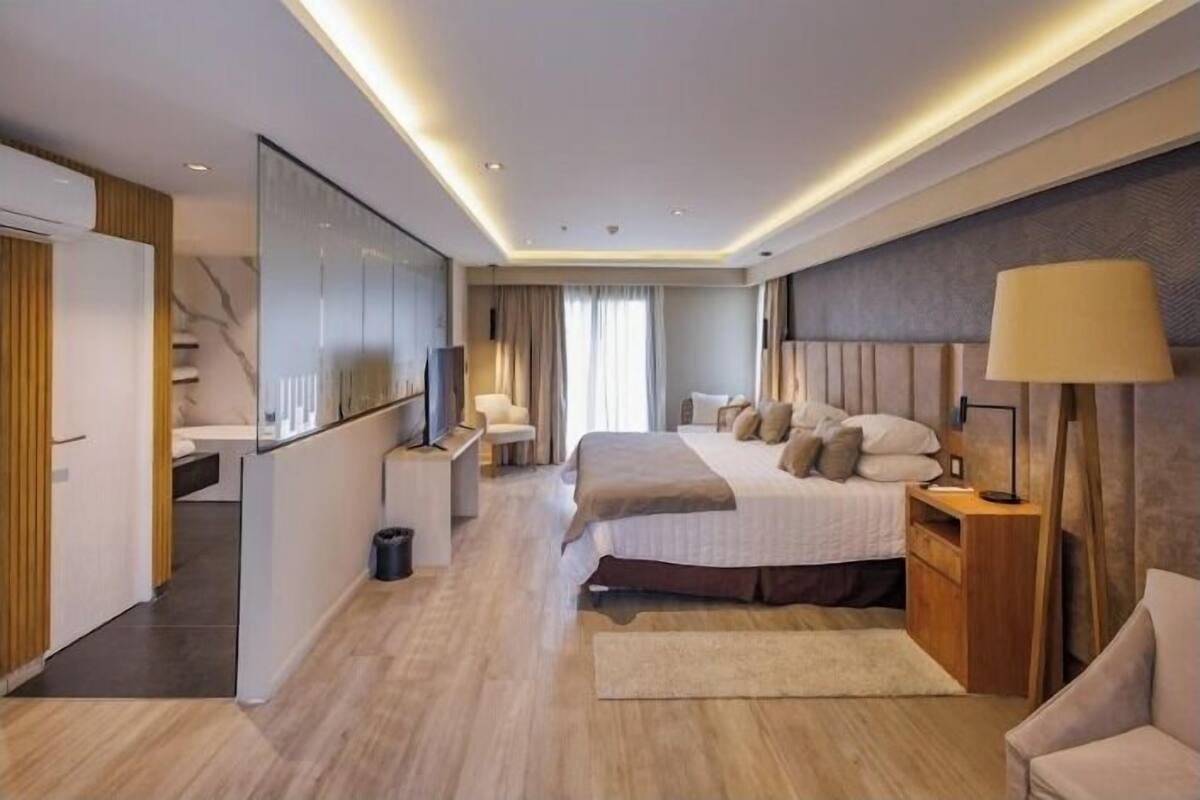 Una habitación de hotel moderna con una cama grande, mesitas de noche, televisión y un armario.
