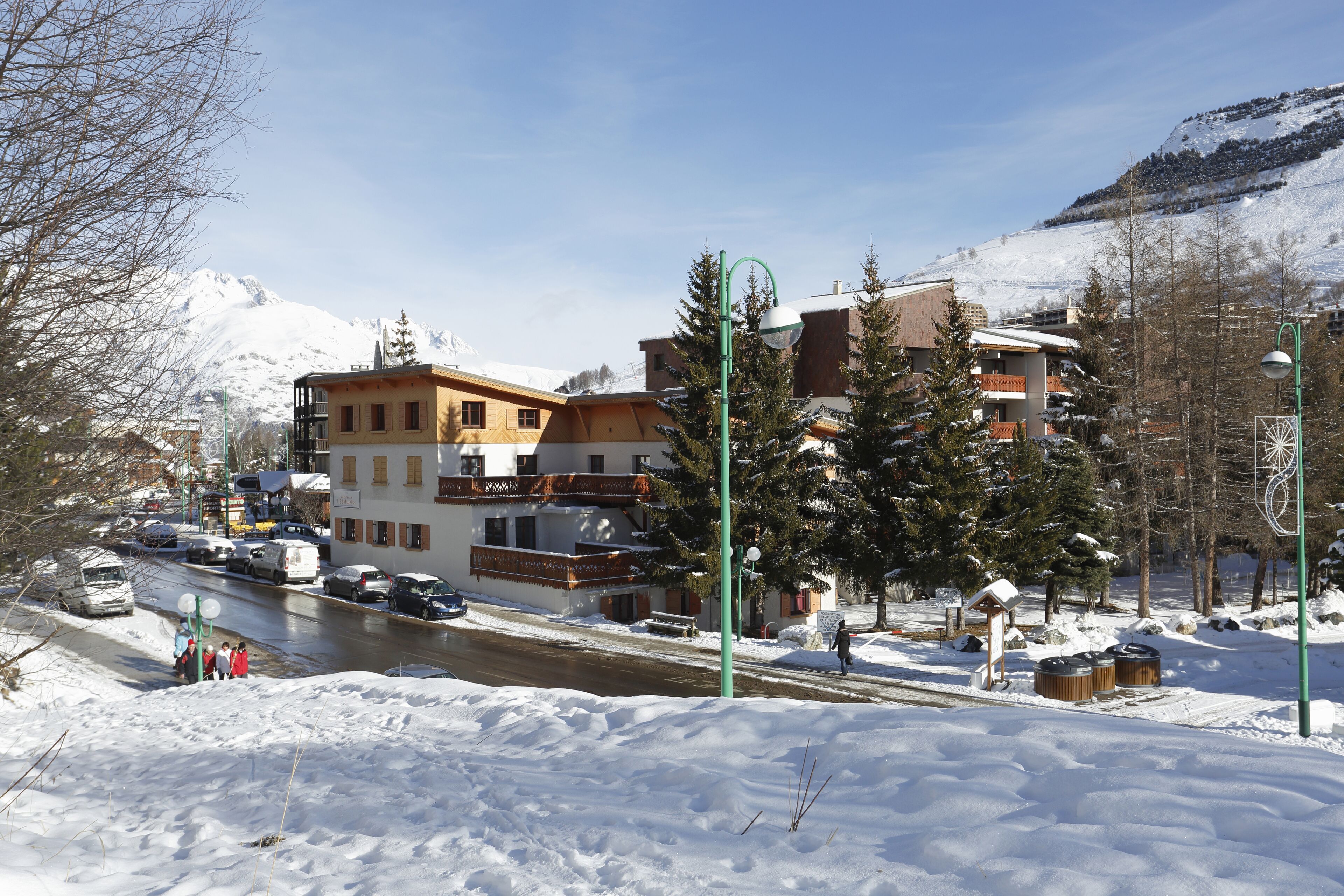 Pueblo cubierto de nieve con edificios, una calle y una montaña al fondo.