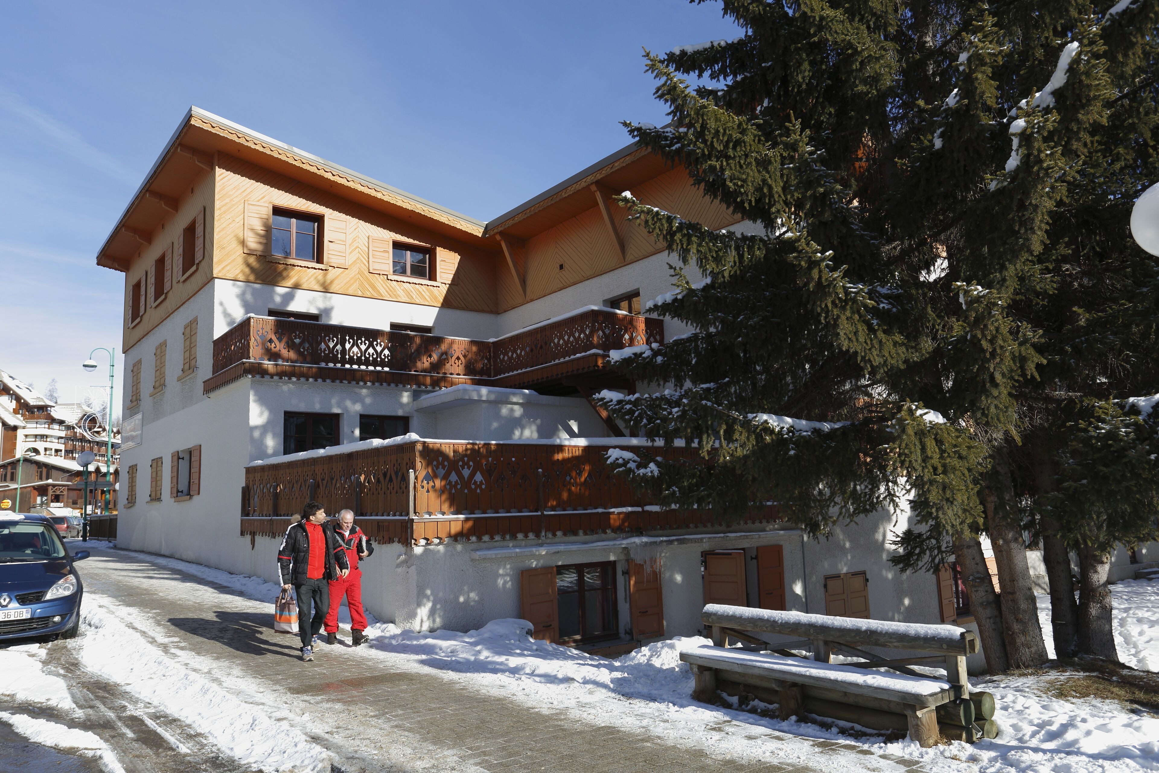 Un immeuble à plusieurs étages, doté d’une façade en bois, de balcons et de neige au sol.