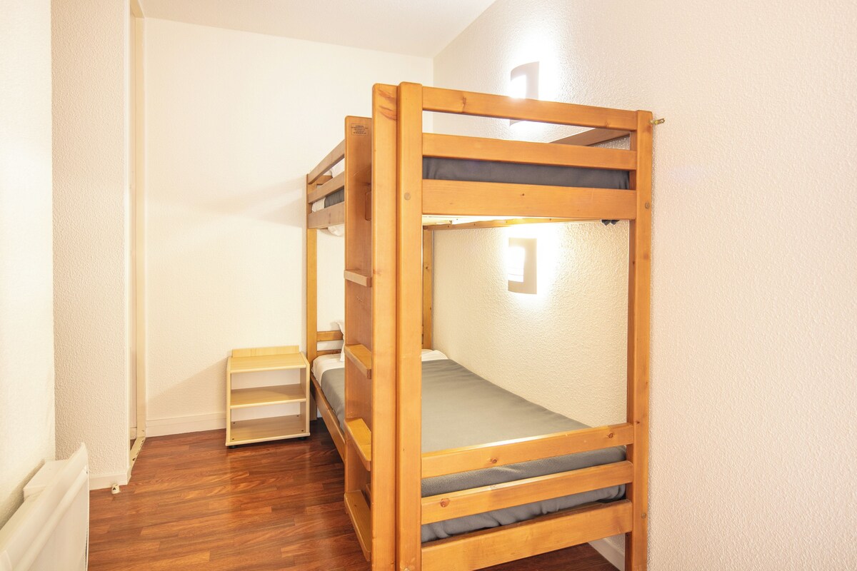 Ein Stockbett in einem Zimmer mit weißen Wänden und Holzdielen.