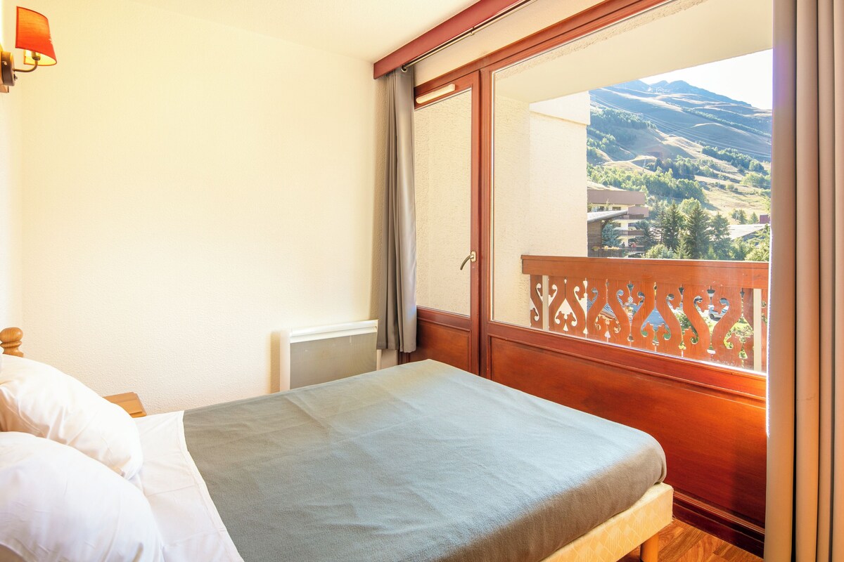 Une chambre à coucher avec un lit, une fenêtre donnant sur la campagne et une balustrade en bois.
