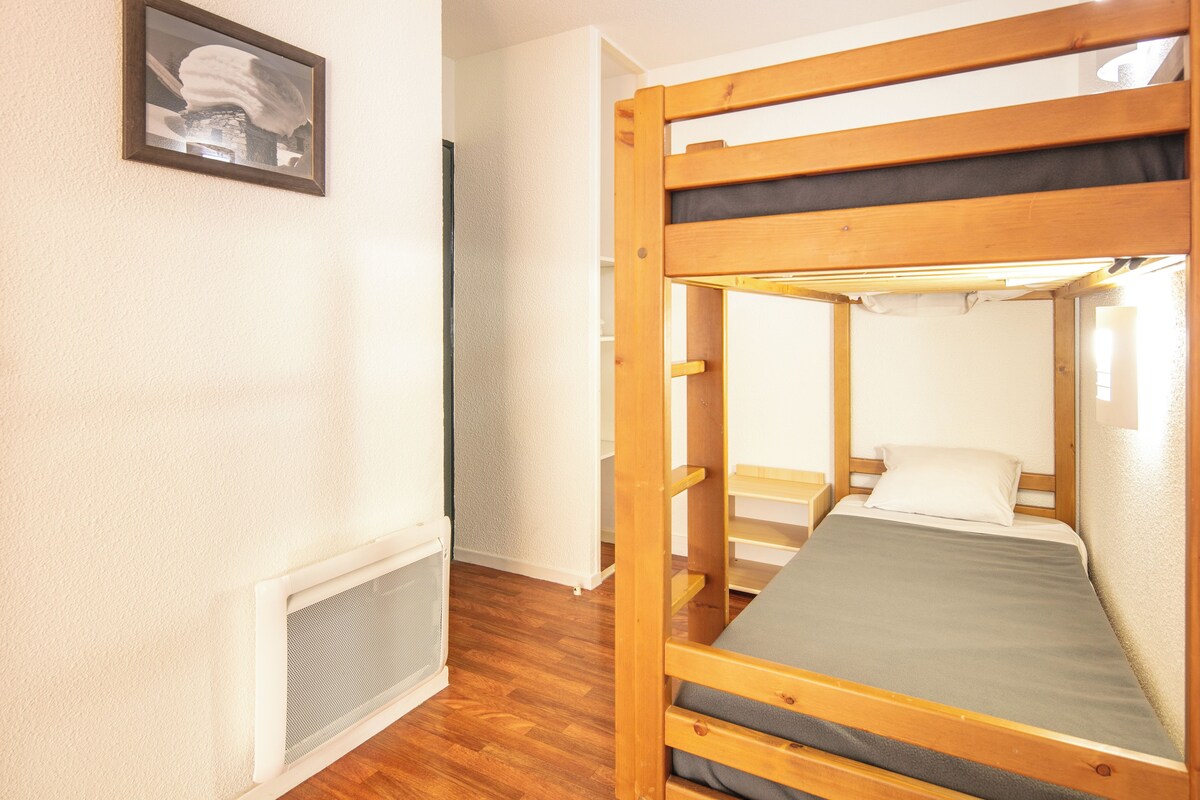 Una cama litera con colchón y almohadas, un radiador y un cuadro en la pared.