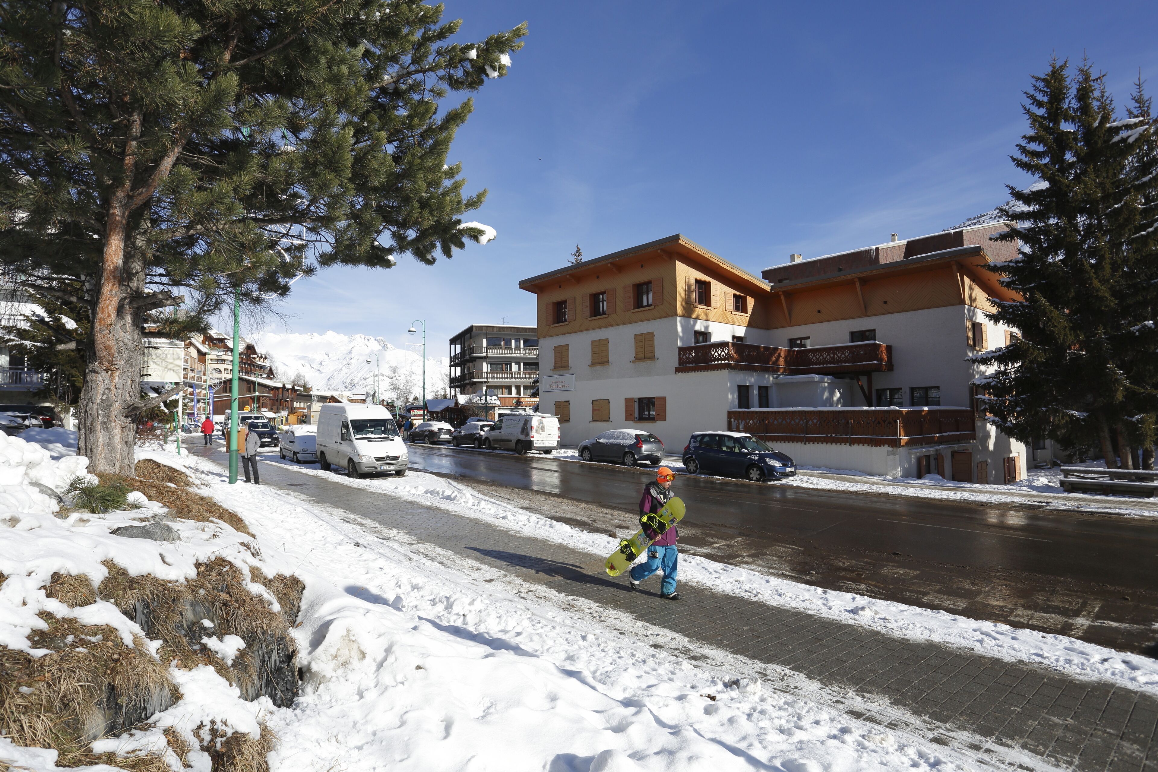 Eine verschneite Straße mit Gebäuden, darunter ein mehrstöckiges Haus mit Balkonen.