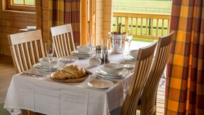 A wooden table set for a meal with chairs, a bottle of champagne, and a basket of bread. - Stable Lodge (Glasgow)