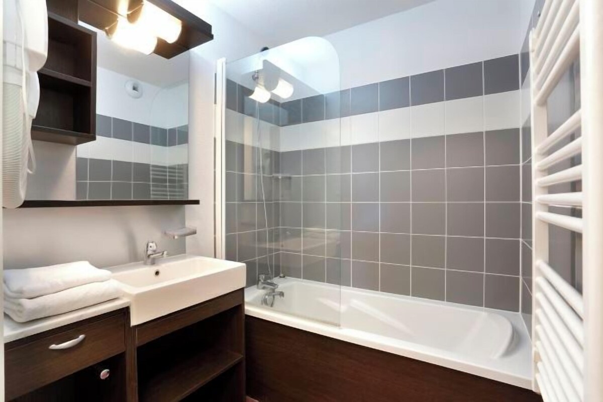 A modern bathroom with a white sink, dark wooden vanity, a glass-enclosed shower, and a white bathtub.