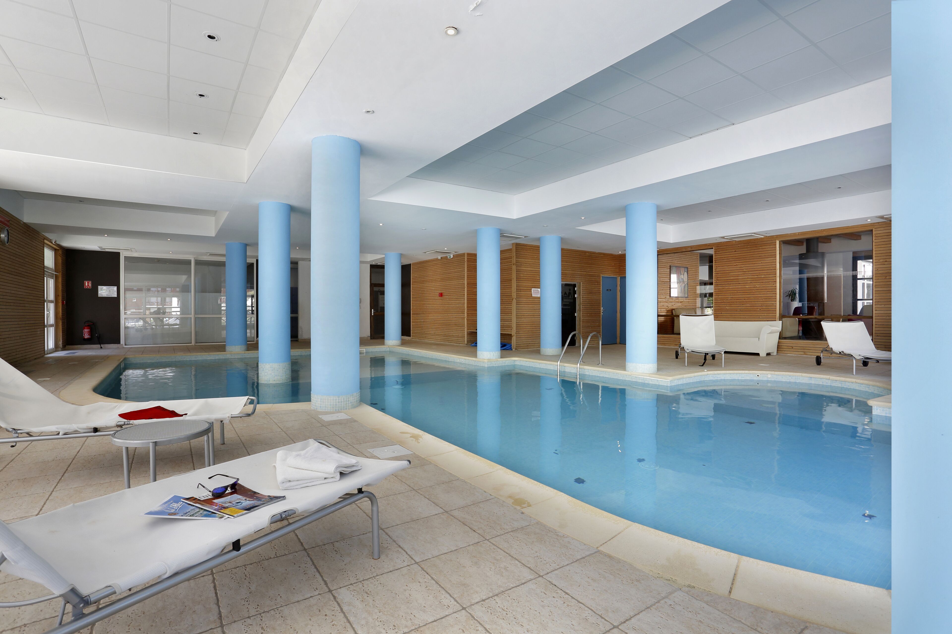 Una piscina interna con lettini e pavimento piastrellato.