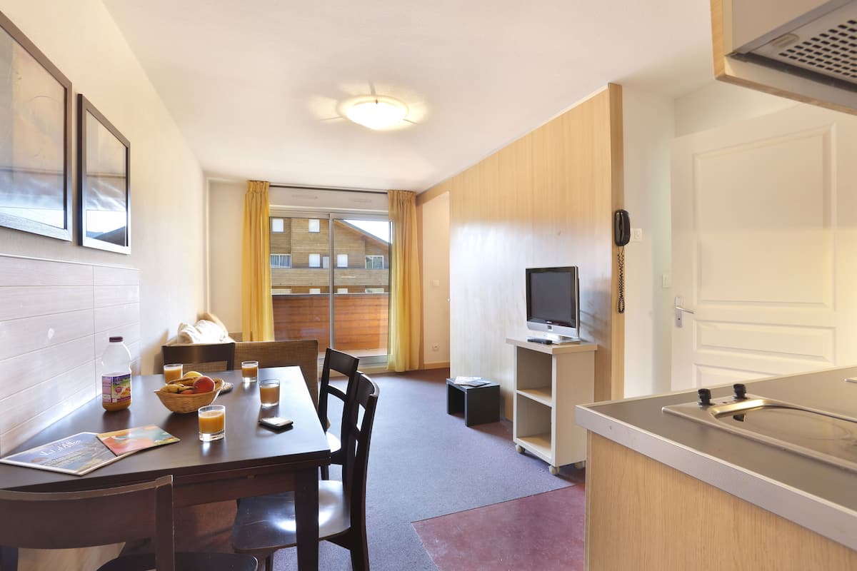 A compact hotel room with a dining area, a small TV, and a phone on the wall.