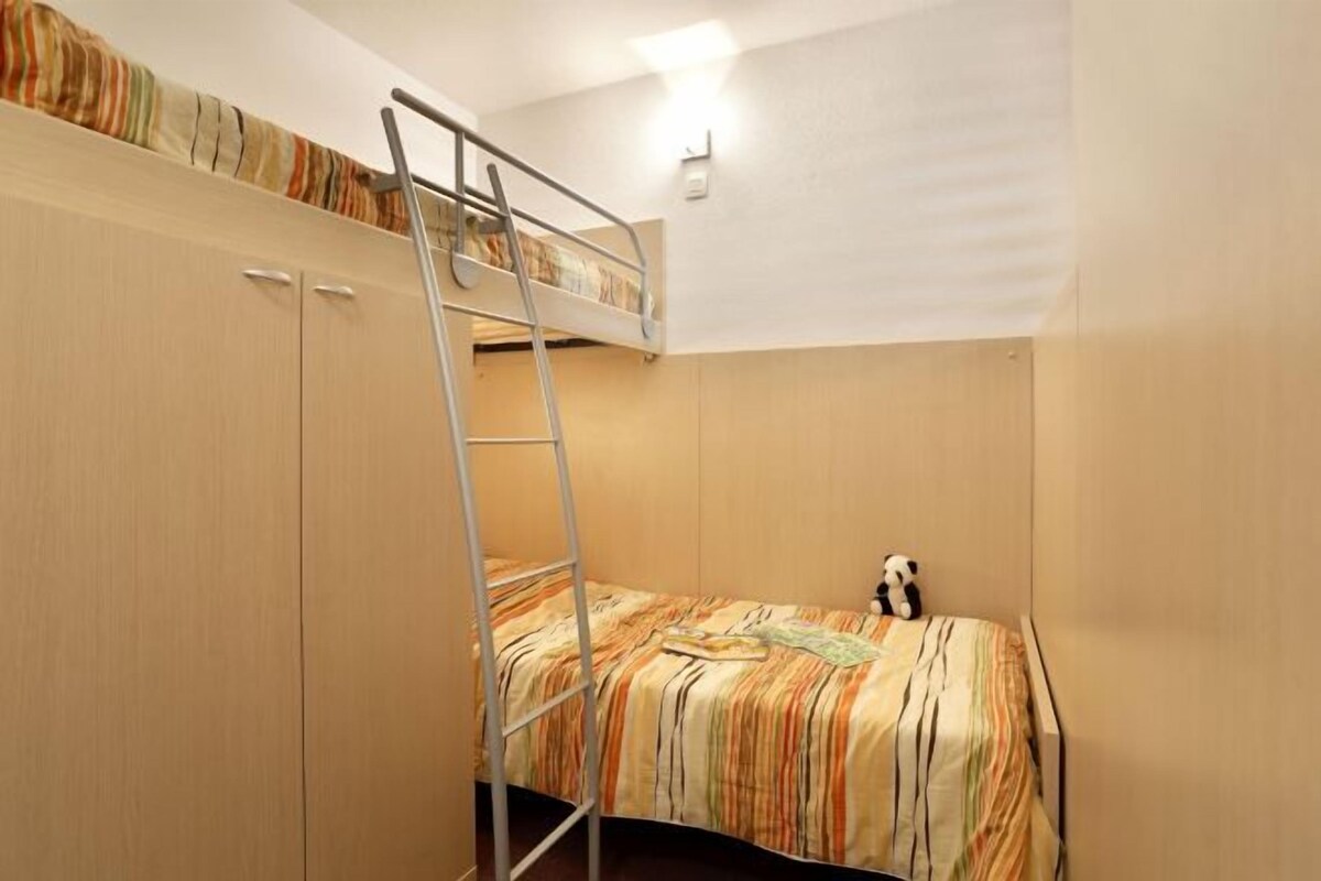 A bunk bed with a ladder, a small bed with a striped blanket, and a panda toy.