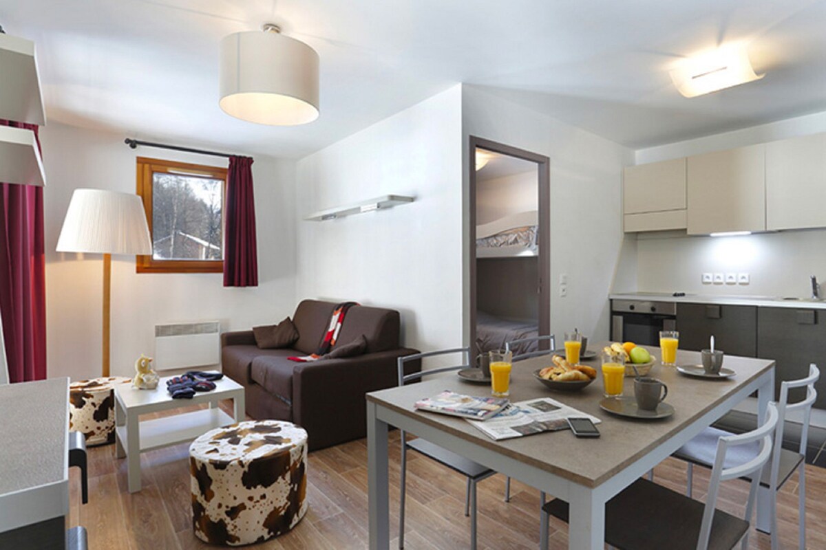 Una habitación de hotel moderna con comedor, sofá, lámpara y vistas al exterior.