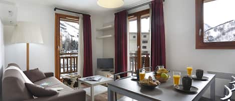 Ett modernt hotellrum med en soffa, ett matbord och en plats för frukost.