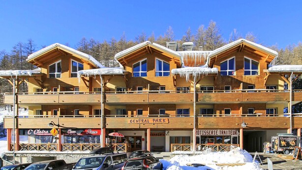Un edificio de madera de varios pisos con balcones, un letrero que dice "CENTRAL PARK" y un restaurante llamado "ROTISSERIE TRAITEUR" en la planta baja.