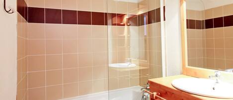 A bathroom with a bathtub, a sink, and a mirror.