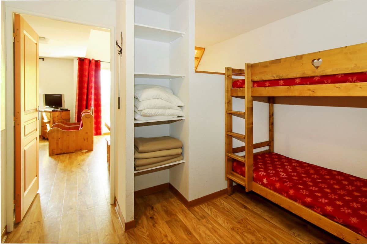 Ein Zimmer mit Etagenbett, Holzmöbeln, Fernseher und Kleiderschrank.