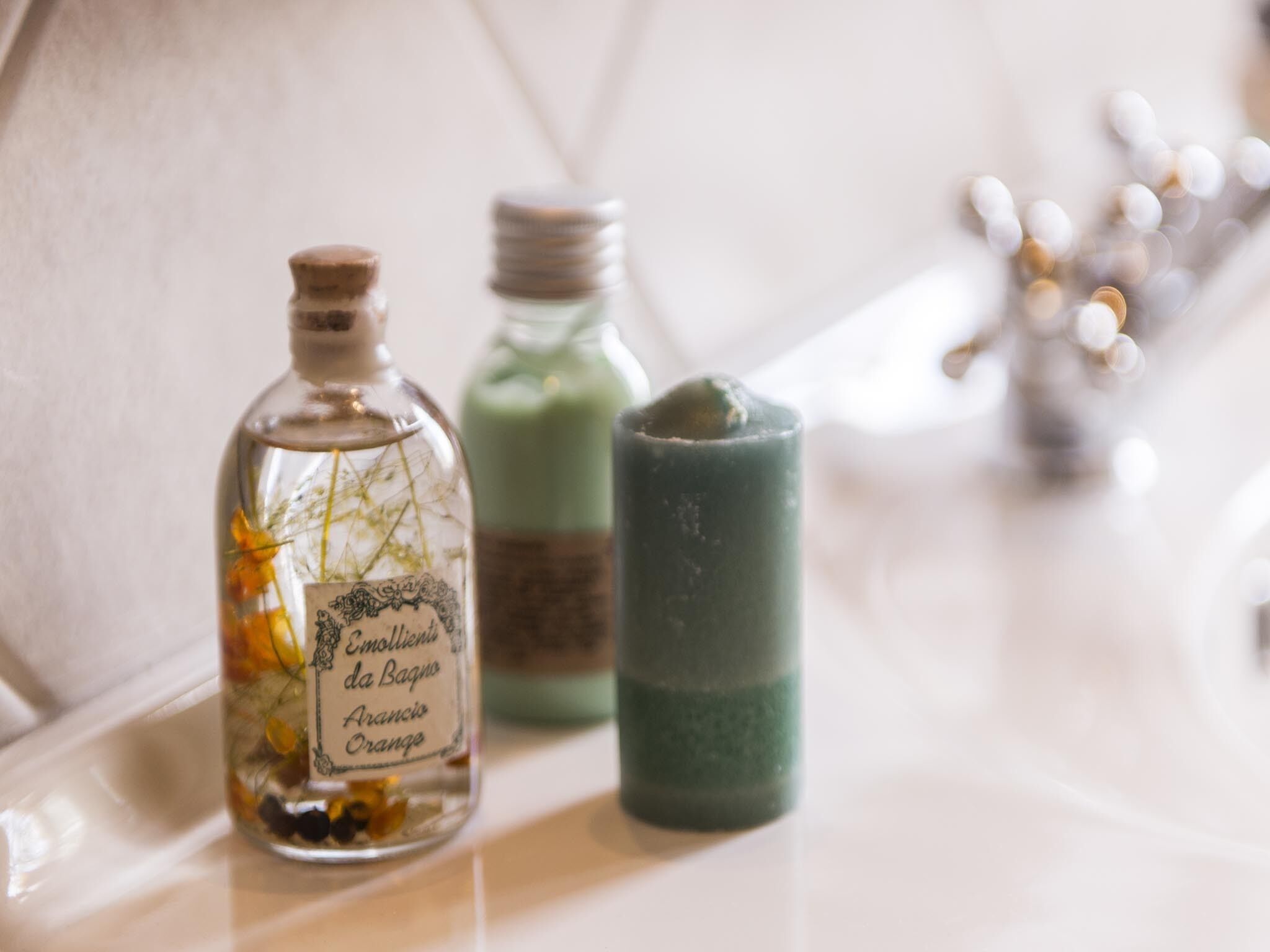 Eine klare Glasflasche mit Etikett, ein grüner Kerzenhalter und verschwommene Lichter im Hintergrund.